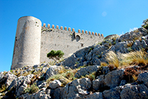 Torre circular sud-oest i muralla del castell del Montgrí. S´aprecien els merlets, les espitlleres i el matacà.