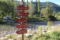 Senyalització vertical amb banderoles al costat del riu, eix vertebrador de la vall.