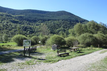 Àrea de pícnic amb taules, bancs i un panell interpretatiu.