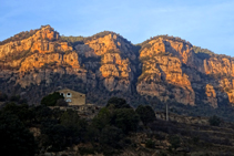 L´emblemàtica masia del Pujol de la Valldora i els cingles de Busa al darrera.