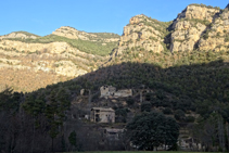 Les masies de Cal Guirre, Cal Teixidor i el Solà, amb les cingleres de Busa al fons.